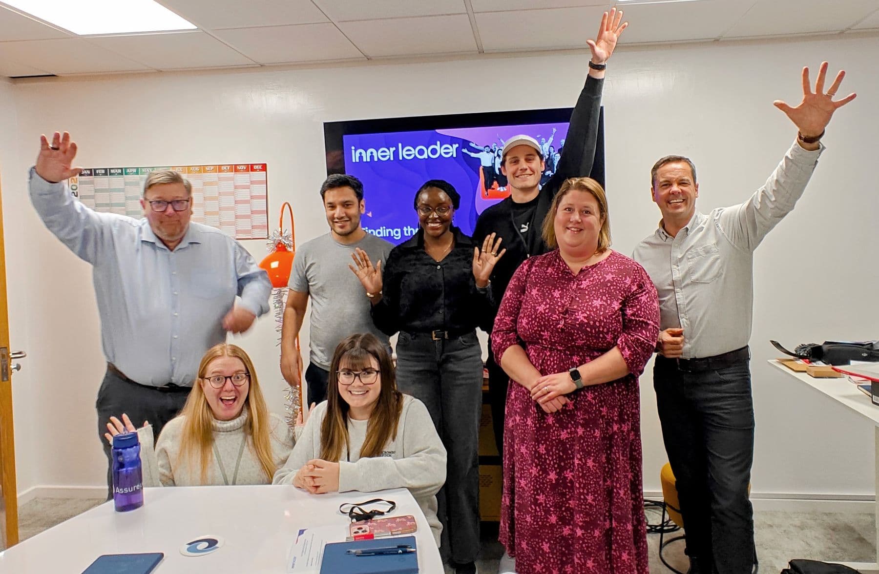A group celebrating with their arms in the air in a training room
