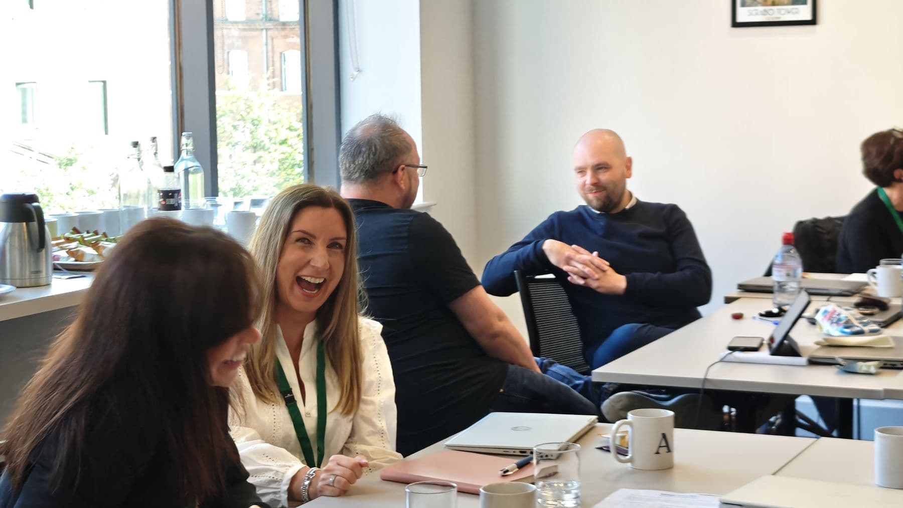 A woman laughing with colleagues around the tables during a workshop