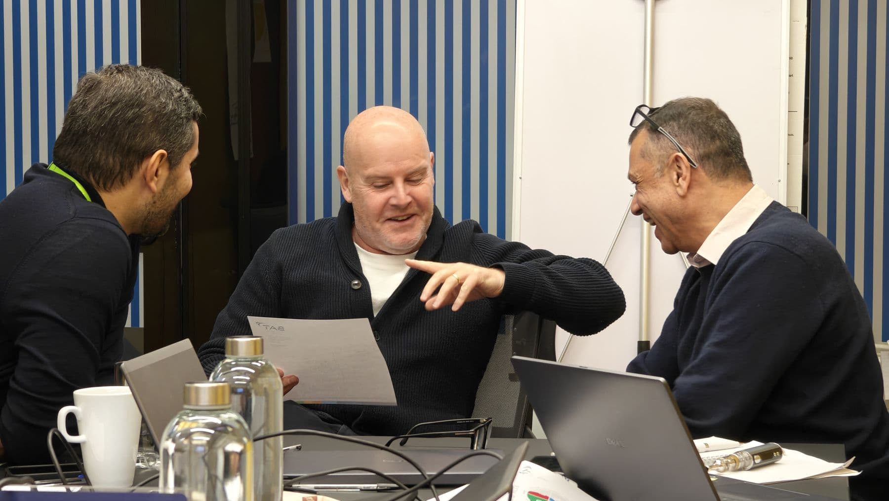 Three colleagues laughing together as they work through an exercise at a table